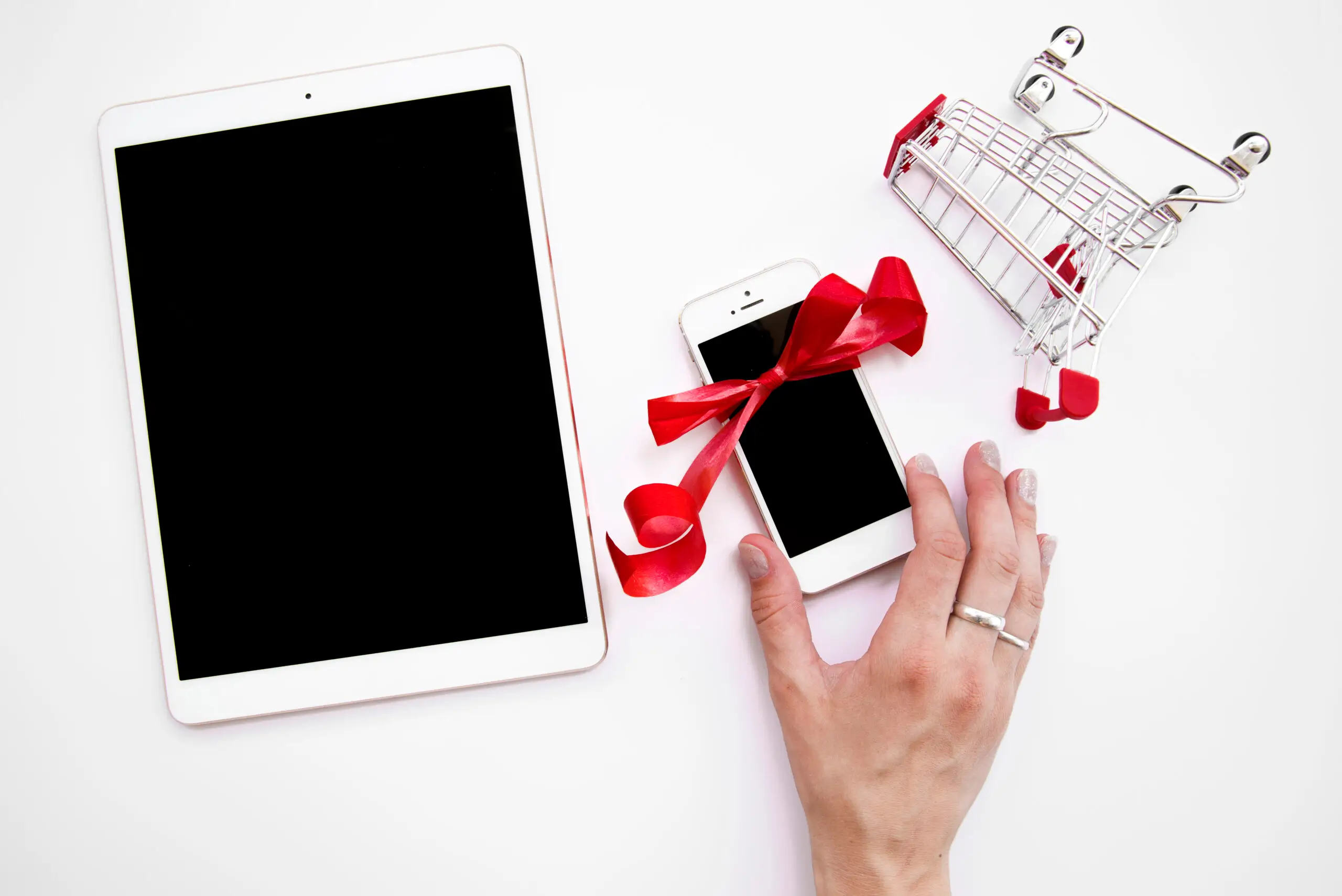 woman-s-hand-smartphone-near-tablet-shopping-trolley-scaled